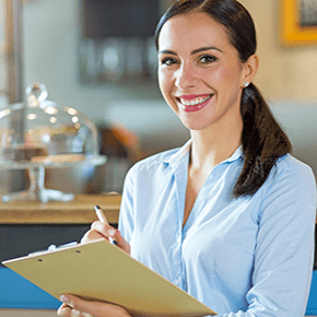 A lady smiling holding a clip board and pen