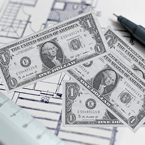 One dollar bills in front of blueprints