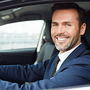Man in car smiling dressing in blue suit