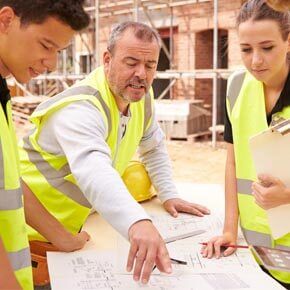 Three construction workers looking at blueprints