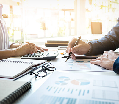 Business man and woman working on financial information the lady is on a calculator and man holding pen with black glasses on desk