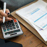 Woman looking at invoice papers while using calculator
