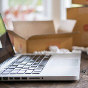 Laptop sitting in front of open boxes with styrofoam filling sitting on table