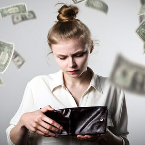Woman looking in wallet with blurred money falling around her