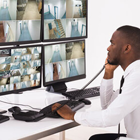 man watching security cameras with phone in hand