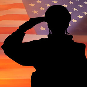 Silhouette of soldier saluting with American flag in background