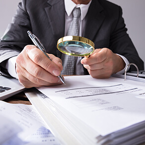 Forensic Accountant looking at financial statements with a magnifying glass