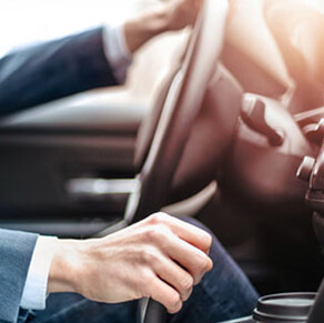 Car steering wheel with drivers hands on wheel