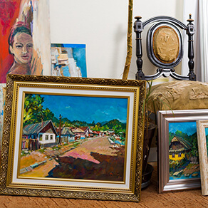 A collection of antiques including multiple paintings and a chair
