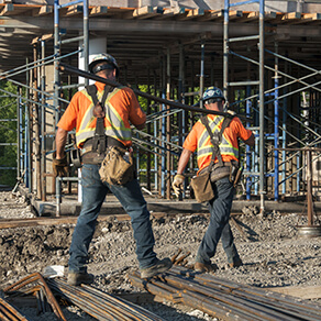 Construction workers transporting metal rods