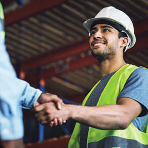 Man in construction vest and hat shaking hands with business man
