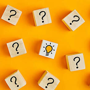 Concept of to find a creative idea or problem solving. Question mark and light bulb icons on wooden cubes on yellow background.