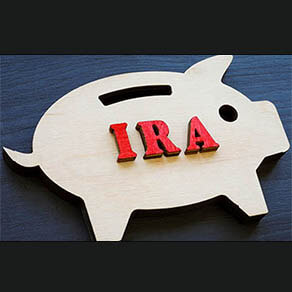 Wooden piggy bank and IRA individual retirement account abbreviation.