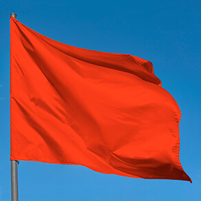 Bright red flag waving against blue sky, blank red banner