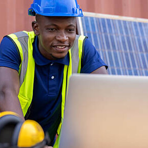 Engineer wearing blue hard hat working on laptop computer at workplace area clean and green alternative energy concept.