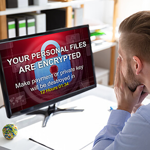Worried Businessman Looking At Computer With Ransomware Word On The Screen At The Workplace