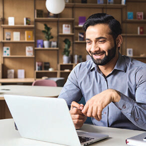 Man sitting at table smiling looking at a laptop