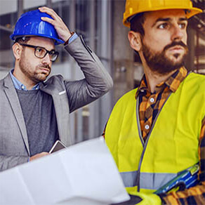 Two men, in construction hats looking stressed and worried