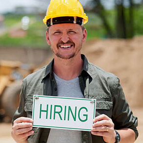 Cropped portrait of a handsome mature construction worker holding a hiring sign while standing on a construction site