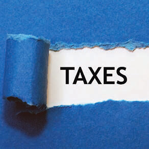 Blue paper ripping to reveal the word taxes underneath