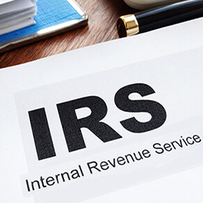 Paper with the words IRS Internal Revenue Service on a desk with other papers