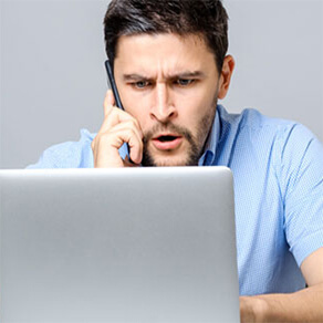 Man looking concerningly at his laptop while on the phone
