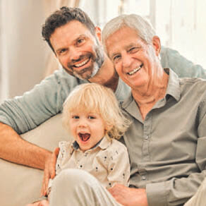 Three individuals who look like a grandfather, a father, and a child smiled for a photo.