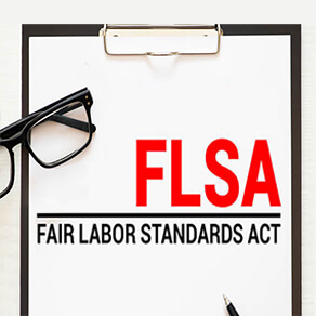 Clip board with FLSA , Fair Labor Standards Act written on it and a pair of glasses