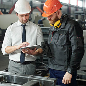 A supervisor standing with an employee looking at a document on a manufacturing site