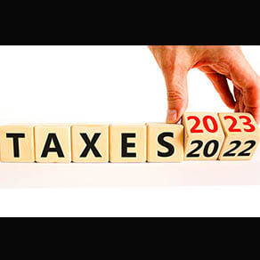 2023 taxes new year symbol. Businessman turns a wooden cube and changes words Taxes 2022 to Taxes 2023. Beautiful white table white background, copy space. Business 2023 taxes new year concept.