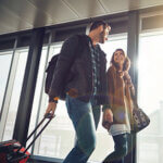 Man and woman walking through airport pulling luggage