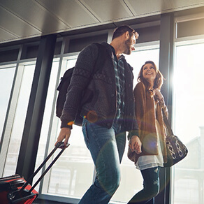 Man and woman walking through airport pulling luggage