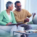 Older couple sitting on a couch looking at documents
