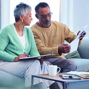 Older couple sitting on a couch looking at documents