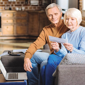 Older man and woman on a couch looking at a piece of mail