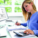 Woman working at a computer and using a calculator