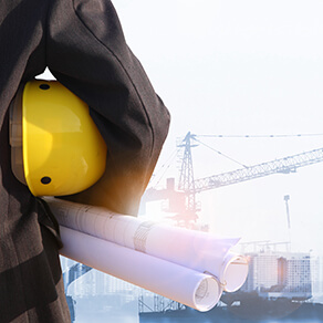 engineer on site holding hard hat and plans