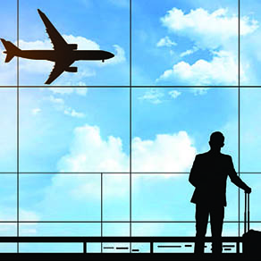 Business man with luggage looking out window at airplane landing