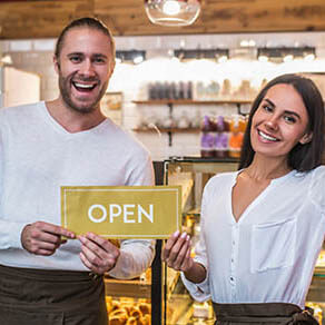 Smiling broadly. Cheerful good-looking husband and wife smiling broadly while opening their own bakery