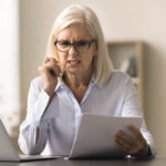 Woman on the phone look at papers in frustration