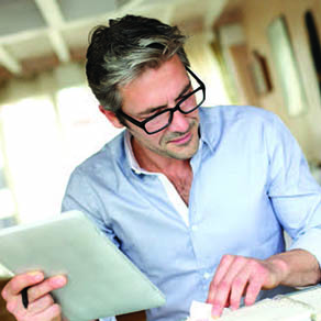 Business man in glasses holding papers and looking through other papers on a desk