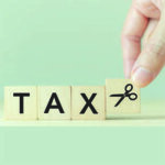 Tiles spelling out the word "TAX" with a hand placing a last title with scissors on it.