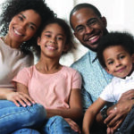 Family of four sitting together and smiling for a photo