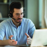 Man with headset; explaining something he is seeing on his computer.