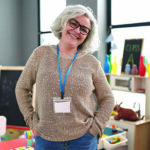 Teacher in a classroom standing with hands on her hips