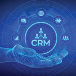 Computer image of hand holding circle with "CRM" written in the middle and images floating around it