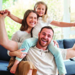 Family photo of husband, wife and daughter smiling and posing for the camera