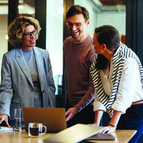 Group of coworkers smiling, in conversation and looking over documents