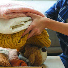 A close up of a woman organizing folded sweaters