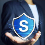 Businessman holding a shield in his hand to mean protecting data or assets from damage